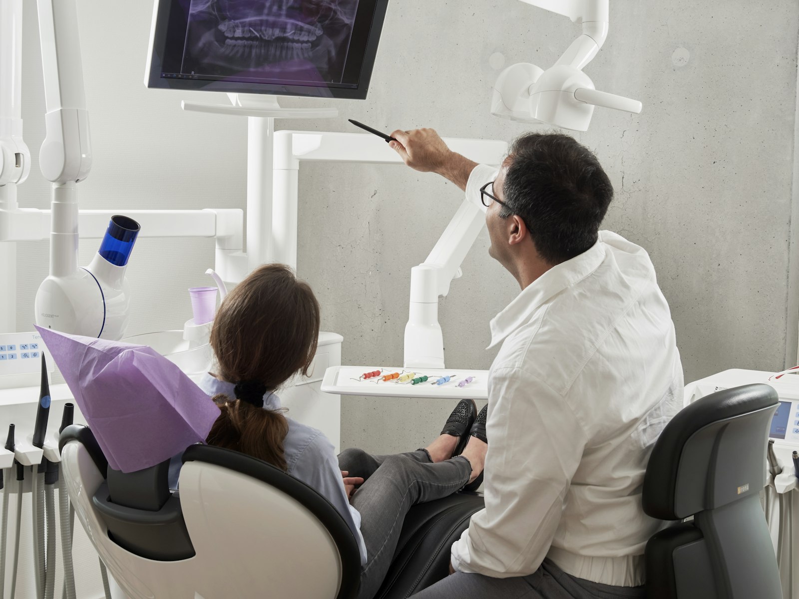 A dentist showing a patient their dental X-ray on a screen