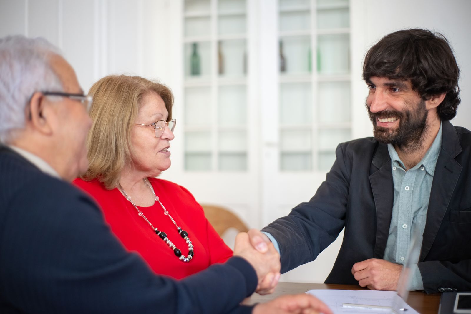 An adviser shaking hands with a senior couple across a table
